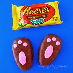 two chocolate peeps with pink paw prints next to a candy bar on a blue background