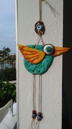 a blue bird hanging from the side of a building with eyes on it's head