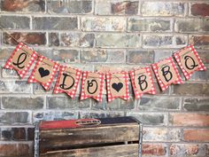 a red and white gingham banner hanging on a brick wall next to an old trunk