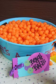 a blue bowl filled with orange candy balls next to a sign that says happy birthday