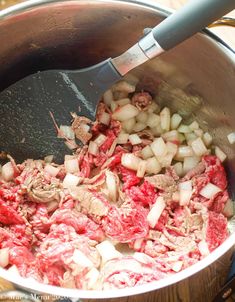 meat and onions cooking in a pot with a ladle on the side, ready to be cooked