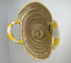 a yellow and white basket hanging from the ceiling with yarn on it's sides