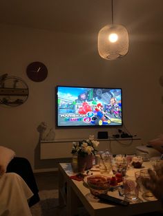 two people sitting in front of a tv playing mario kart on the nintendo wii