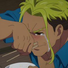 a man with green hair eating food from a bowl and chopsticks in his hand