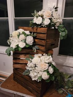 a stack of wooden crates with white flowers on top and greenery in the middle