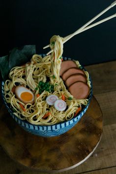 a bowl of noodles with chopsticks sticking out of it on a wooden table