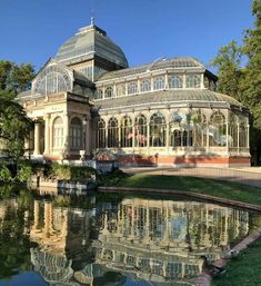 a large glass house sitting on top of a lush green field next to a lake