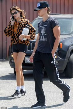 a man and woman walking down the street while talking on their cell phones with one another