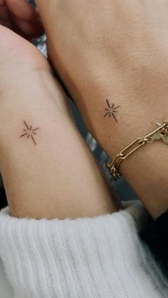 two people with matching tattoos on their arms, one is holding the other's hand