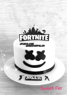 a white cake with black lettering and a smiley face on the top that says fortnite