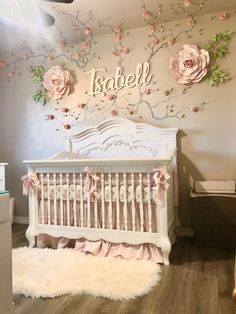 a baby's room decorated in pink and white with flowers on the wall, crib