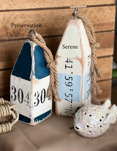 two wooden buoys are sitting on a table next to a rope and sea urn