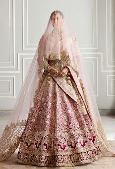 a woman in a pink and gold bridal gown with a veil on her head