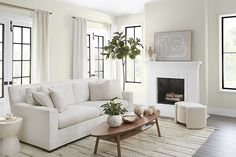 a living room filled with furniture and a fire place in front of a window covered in white curtains