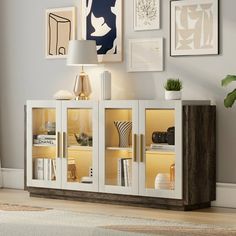 a white and brown cabinet with some pictures on the wall behind it in a living room