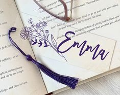 an open book with the word enna written on it and a purple tassel