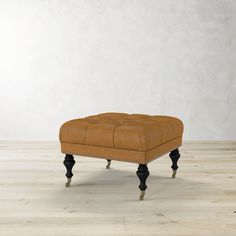 the foot stool is upholstered with black legs and an old - fashioned leather cushion