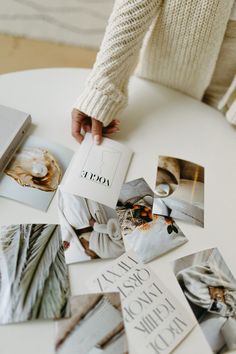 a table topped with lots of different pictures and photos on it's surface next to a person holding a book