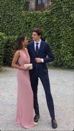 a man in a suit and tie standing next to a woman wearing a pink dress