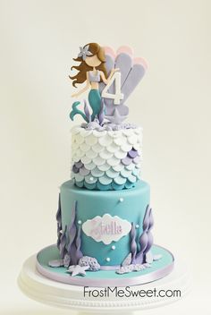 a blue and white cake with a little mermaid on top