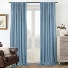 a living room with blue curtains and a brown chair