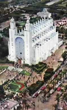 an aerial view of a large white building in the middle of a city with lots of people around it