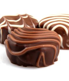 three pieces of chocolate with white and brown swirls on top, sitting next to each other