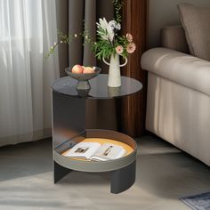 a glass table with an open magazine on it next to a couch and vase filled with flowers