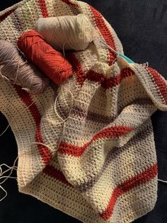 two skeins of yarn sitting on top of a white and red striped blanket