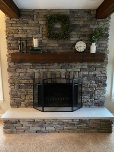 a stone fireplace with a mantle and clock above it