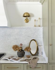 a kitchen with marble counter tops and gold accents on the cabinetry, along with an oval mirror