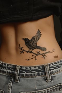 a woman's stomach with a bird tattoo on her belly and the bottom part of her lower body