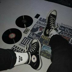 there is a person standing on the floor with their feet up next to some records