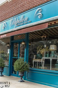 the storefront of an antique furniture and home decor store with two large planters in front