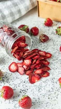 strawberries are spilled out of a jar on a table