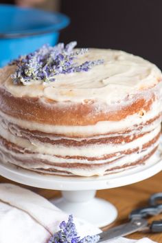 a cake with frosting and lavender sprinkles sits on a white plate