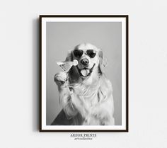 a black and white photo of a dog wearing sunglasses holding a martini glass in its mouth