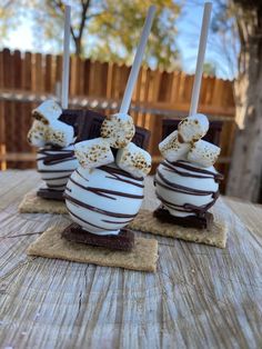 three chocolate covered desserts sitting on top of a wooden table