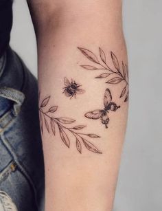 a woman's arm with tattoos on it and some flowers in the middle,