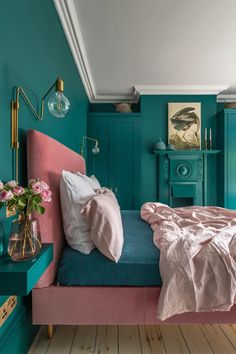 a bedroom with teal walls and pink bedding in the center, along with blue nightstands