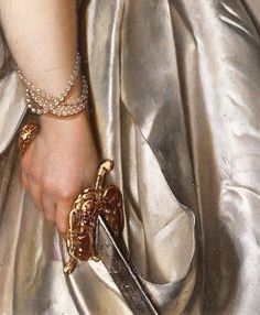 a close up of a person holding a pair of scissors in their hand and wearing a silver dress