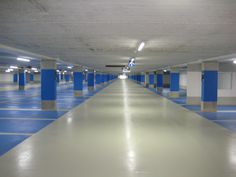 an empty parking garage with blue and white painted flooring on the walls, along with several columns