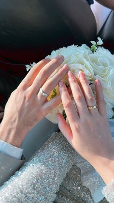 the bride and groom are holding their wedding rings over each other's hands as they sit together