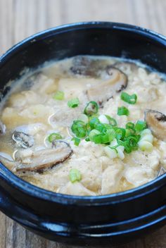 a close up of a bowl of food on a table with green onions and mushrooms