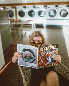 a woman sitting in a laundry room reading a magazine with an image of a man on the cover