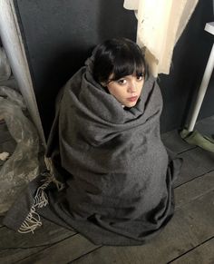 a woman wrapped in a blanket sitting on the floor