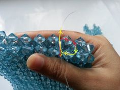 a hand holding some blue glass beads with yellow thread in it's middle and the end of each bead