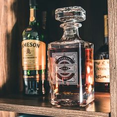 an empty glass bottle sitting on top of a wooden shelf next to bottles of liquor