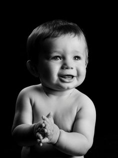 a black and white photo of a baby with his hands folded in front of him