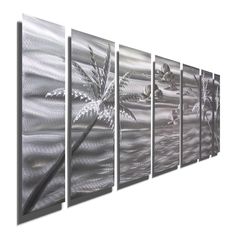 a set of four metal wall hangings with palm trees and water in the background